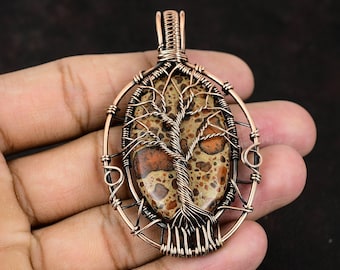 May include: A copper wire wrapped pendant featuring a brown and red tree agate stone. The stone is set in a wire frame that resembles a tree with branches and roots.