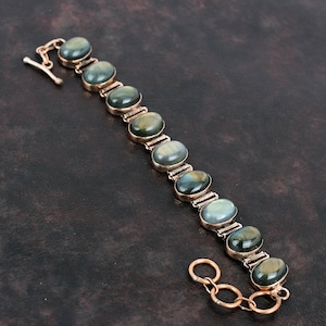 May include: A silver bracelet with a chain and oval-shaped green gemstones.