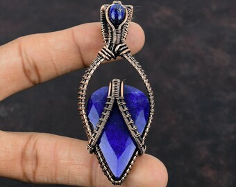 May include: A teardrop-shaped lapis lazuli gemstone pendant wrapped in copper wire. The pendant has a smaller lapis lazuli stone at the top.