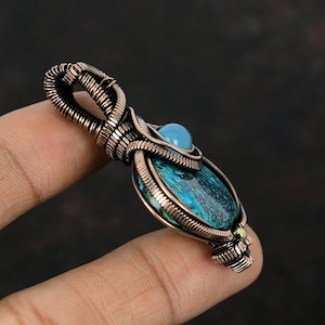 May include: A copper wire wrapped pendant featuring a blue and green gemstone with a smaller blue gemstone at the top.