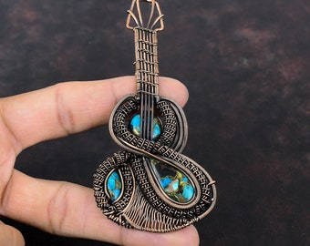 May include: A copper wire guitar pendant with turquoise and black stones. The pendant is intricately woven and features a detailed guitar shape.