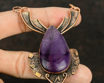 May include: A copper pendant with an intricate design features a large, teardrop-shaped amethyst gemstone. The pendant has a textured, aged look and is perfect for adding a touch of bohemian style to any outfit.