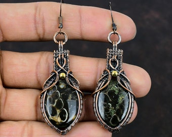 May include: A pair of copper wire wrapped earrings with black and green agate stones. The earrings are teardrop shaped and have a gold bead accent.