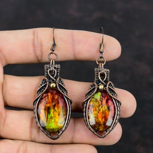 May include: A pair of copper wire wrapped earrings with a large oval shaped iridescent gemstone in the center of each earring.