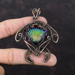 May include: A copper wire wrapped pendant featuring a iridescent abalone shell in the center. The pendant is shaped like a seashell with intricate wire details.