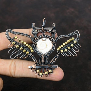 May include: A wire-wrapped owl pendant with a white shell inlay and gold beads. The owl is made of copper wire and has a detailed design.