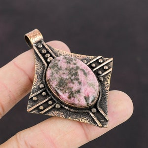 May include: A pink and green gemstone pendant with an ornate silver setting. The pendant is shaped like a diamond and has a detailed design.