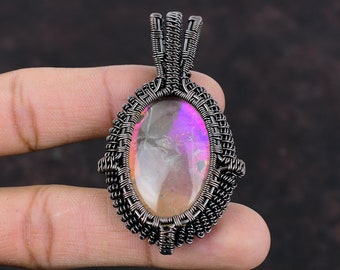 May include: A silver wire wrapped pendant featuring a large oval iridescent gemstone with pink and purple hues.