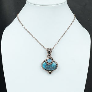 May include: A copper wire wrapped pendant necklace featuring a blue and green gemstone with a smaller light blue gemstone accent.