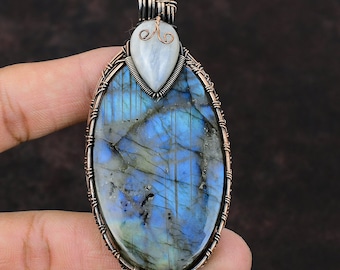 May include: A copper wire wrapped pendant featuring a large oval blue labradorite gemstone and a smaller teardrop shaped moonstone.