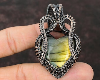 May include: A heart-shaped pendant with a green and yellow labradorite gemstone set in a silver wire wrapped frame.