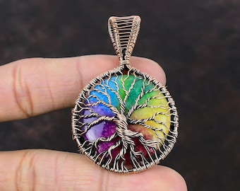 May include: A rainbow chakra tree of life pendant made with copper wire wrapped around a colorful agate stone. The pendant is oval shaped and has a copper bail for hanging.