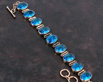 May include: A silver bracelet with a chain and a clasp. The bracelet is adorned with oval-shaped blue gemstones.