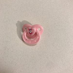 以下が含まれることがあります： 白とピンクの漫画のネズミのデザインが施されたピンクの哺乳瓶