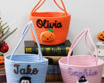 May include: Three round rope baskets in orange, light blue, and light pink with two handles each. The orange basket features the name Olivia and a pumpkin patch. The blue basket says Jake with a character patch. The pink basket says Sophia with a ghost.