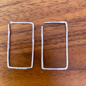 May include: A pair of silver rectangle shaped earrings with a hammered texture.