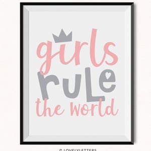 Può includere: Una stampa incorniciata con le parole "girls rule the world" in lettere rosa e grigie. Una corona grigia è sopra la parola "girls", e un cuore sostituisce la lettera "o" in "rule". La stampa è in una cornice nera.