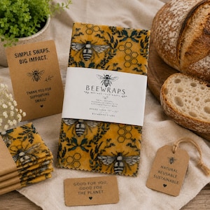 May include: A rectangular beeswax food wrap featuring a yellow background with a dark green botanical pattern and bee illustrations. A white paper band displays the text BEEWRAPS, BREAD WRAP 17" x 23", and BEEWRAPS.STORE. Includes matching cards and a tag.