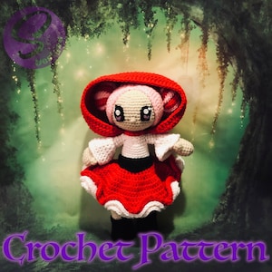 May include: Crochet pattern for a red hooded girl doll with pink hair and white dress. The doll is standing in front of a green and white background.
