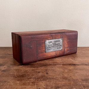 May include: A small wooden box with a metal plaque that reads "OAK TIMBER FROM U.S. FRIGATE CONSTITUTION 1797 1840".