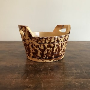 Może przedstawiać: Wazon ceramiczny w stylu vintage w kremowym kolorze z brązowym, nakrapianym wzorem. Wazon ma zaokrąglony kształt z dwoma uchwytami i szerokim otworem. Wnętrze jest jaśniejsze kremowe.