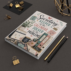 May include: A white notebook with a graphic illustration of office supplies, a calendar, and a coffee mug. The cover features the text: Secretary: Keeper of the CALENDAR, SOLVER of the PROBLEMS, along with small hearts, leaves, and stars in pink and green.