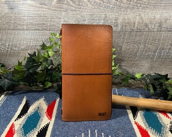 May include: A brown leather notebook cover with the word "MAT" embossed on the front.