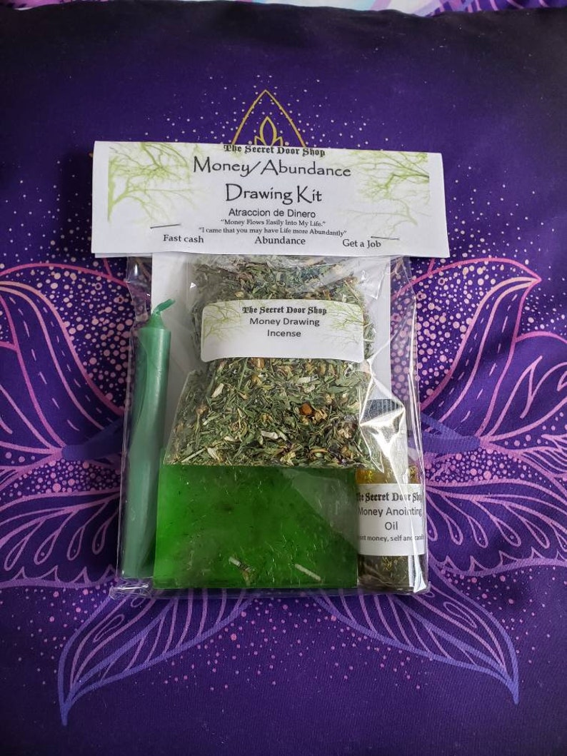 Peut inclure: Un sac en plastique transparent contenant un kit de tirage d'argent. Le kit comprend une bougie verte, un petit sac d'herbes vertes &eacute;tiquet&eacute; "Encens de tirage d'argent", une barre de savon verte et un petit flacon d'huile &eacute;tiquet&eacute; "Huile d'onction d'argent". Le sac comprend &eacute;galement une carte avec le texte "The Secret Door Shop Money/Abundance Drawing Kit Atraccion de Dinero "Money Flows Easily Into My Life" "I came that you may have Life more Abundantly" Abundance Fast cash Get a Job"