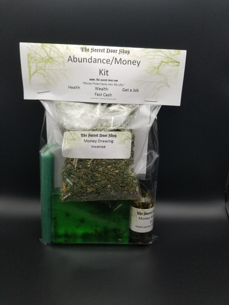 Peut inclure: Un sac en plastique transparent contenant une bougie verte, un savon vert, une petite bouteille d'huile et un sachet d'herbes s&eacute;ch&eacute;es. Le sac est &eacute;tiquet&eacute; "The Secret Door Shop Abundance/Money Kit" et comprend le texte "Money Flows Easily Into My Life."  "Health, Wealth, Fast Cash, Get a Job."  "The Secret Door Shop Money Drawing Incense."