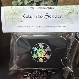 May include: A rectangular black metal tin in clear plastic packaging with a header card reading The Secret Door Shop, Return to Sender, and the quote Return what is not yours. Not everything is yours to carry. The tin features a holographic geometric design.