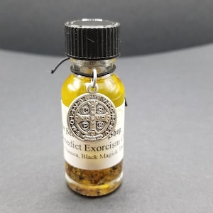 May include: A small glass bottle filled with a yellow liquid and small dark particles. The bottle has a black cap and a silver charm with a cross and the words "Saint Benedict" hanging from it. The label on the bottle reads "Saint Benedict Exorcism Oil - Nausea, Black Magick, etc. Shop (website address)"