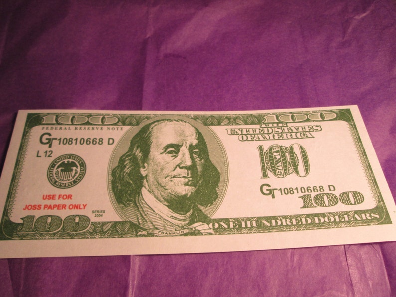 Peut inclure: Un billet de 100 dollars am&eacute;ricain vert et blanc avec un portrait de Benjamin Franklin. Le billet est marqu&eacute; "USE FOR JOSS PAPER ONLY" et porte le num&eacute;ro de s&eacute;rie "Gr10810668 D".