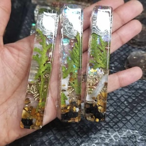May include: Three clear rectangular resin blocks with gold glitter, small stones, and green foliage inside. The blocks are approximately 3 inches long and 1 inch wide.