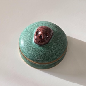Peut inclure: Une tasse en céramique blanche avec une anse noire et le texte "But First, Coffee" en gras noir. La tasse est posée sur un fond flou, suggérant un cadre chaleureux.