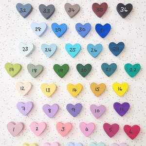 K&ouml;nnte beinhalten: Eine Karte mit 38 herzf&ouml;rmigen Buntstiften in verschiedenen Pastellfarben, darunter Gelb, Rosa, Blau, Gr&uuml;n und Lila. Die Stifte sind von 1 bis 38 nummeriert.