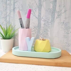 K&ouml;nnte beinhalten: Ein Schreibtisch-Organizer-Set in Hellblau, Gr&uuml;n, Rosa und Gelb mit einem Tablett, einem Stiftehalter, einem kleinen Beh&auml;lter und dem Buchstaben 'Y'.