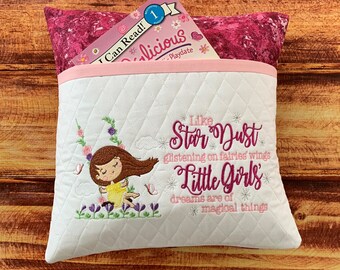May include: White quilted pillow with a pink pocket and a pink and white embroidered design. The design features a girl with brown hair, flowers, butterflies, and the text "Like Star Dust glistening on fairies wings Little Girls' dreams are of magical things".