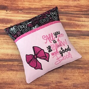 May include: Pink and black pillow with a pink bow and the text "All you need is a big bow and a good book".