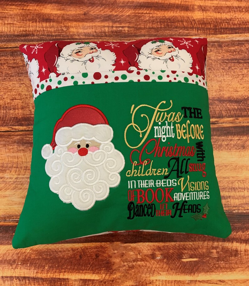 K&ouml;nnte beinhalten: Ein weihnachtliches Kissen mit gr&uuml;nem Grund und einem rot-wei&szlig; gemusterten Oberteil. Es zeigt einen gestickten Weihnachtsmann und den Text "Twas the night before Christmas".