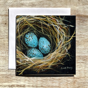 May include: A painting of a bird's nest with three blue speckled eggs inside. The nest is made of twigs and is set against a black background. The artist's signature, "Eukel Avery", is in the bottom right corner.