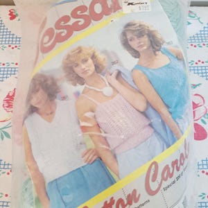 May include: A plastic bag containing a vintage sewing pattern titled "Cotton Carol." The pattern features images of three women wearing knitted tops and skirts. The bag has a Kmart price tag.