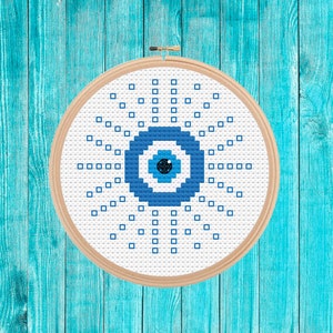 以下が含まれることがあります： 青い目と白い目のデザインが施された白い刺繍枠。青い目は、不運や嫉妬から身を守るお守りの象徴です。