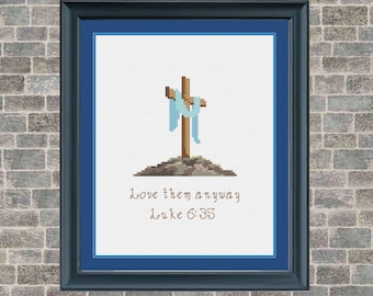 Könnte beinhalten: Kreuzstichmuster mit einem Holzkreuz, über das ein blaues Tuch gelegt ist, vor weißem Hintergrund. Der Text "Love them anyway Luke 6:35" befindet sich unter dem Kreuz.