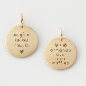 May include: Two gold-toned round metal charms with engraved text. The first charm reads "waylon tucker sawyer" with a heart symbol. The second charm reads "armando ava ajax waffles" with a heart and paw print symbol.