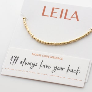 Peut inclure: Bracelet en perles dorées avec une carte qui dit "LEILA" et "Message en code Morse : Je serai toujours là pour toi".