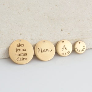 Könnte beinhalten: Vier goldfarbene Metallscheiben mit graviertem Text. Die größte Scheibe trägt die Aufschrift "alex jenna emma claire". Die nächstgrößte Scheibe trägt die Aufschrift "Nana". Die dritte Scheibe trägt die Aufschrift "A 10.2.20". Die kleinste Scheibe trägt die Aufschrift "everett".