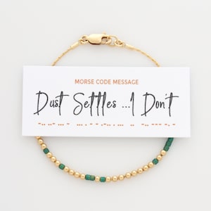 May include: Gold bracelet with green beads and a card that reads "Dust Settles... I Don't" in Morse code.