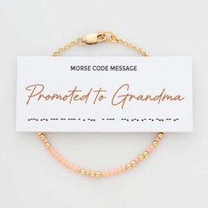 May include: A delicate beaded bracelet with a peach and gold color scheme. The bracelet has a clasp closure and comes with a card that reads "Morse Code Message Promoted to Grandma" and includes the message in Morse code.
