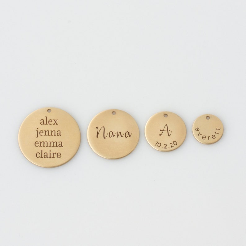 May include: Four gold-colored metal discs with engraved text. The largest disc reads "alex jenna emma claire". The next largest disc reads "Nana". The third disc reads "A 10.2.20". The smallest disc reads "everett".