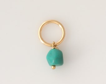 May include: A gold hoop earring with a turquoise gemstone charm. The charm is a rough, irregular shape.